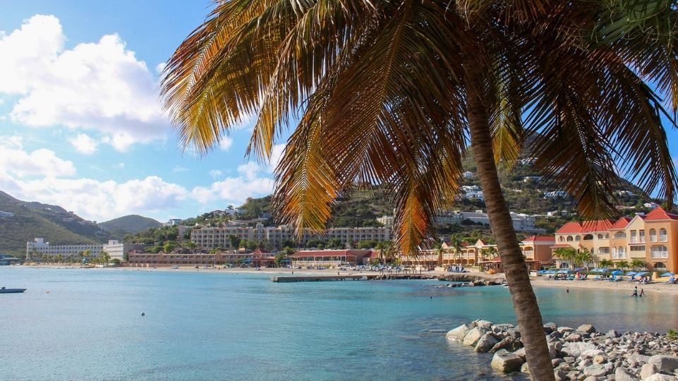 View from Fort Amsterdam to Little Bay Beach, palm tree and Divi Little Bay Beach Resort during a partially cloudy day on St Maarten / St Martin