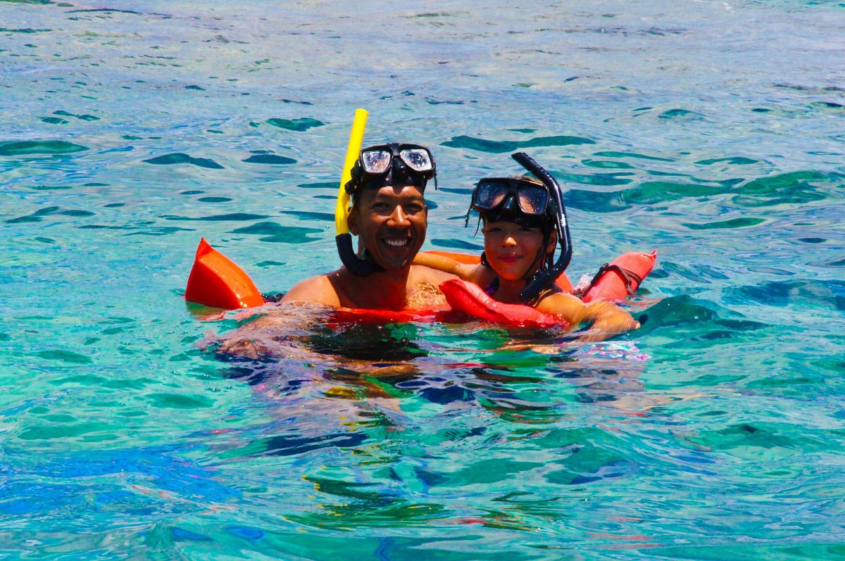 Father and girl in blue sea with snorkels on SXM