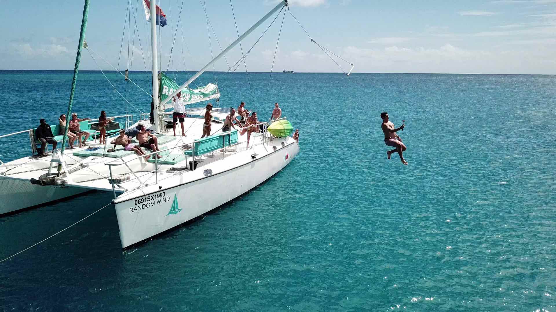 The Tarzan swing with many jumping in water aboard Random Wind Charters yacht