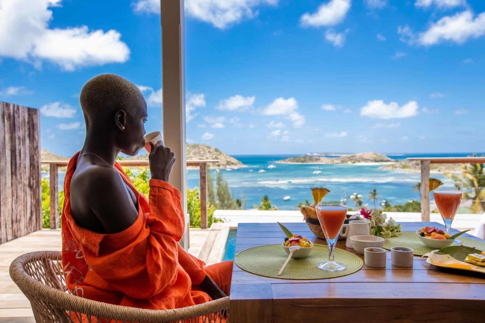 Woman sipping cofffee on balcony overlooking ocean at le-karibuni-boutique-hotels in St MarAtin
